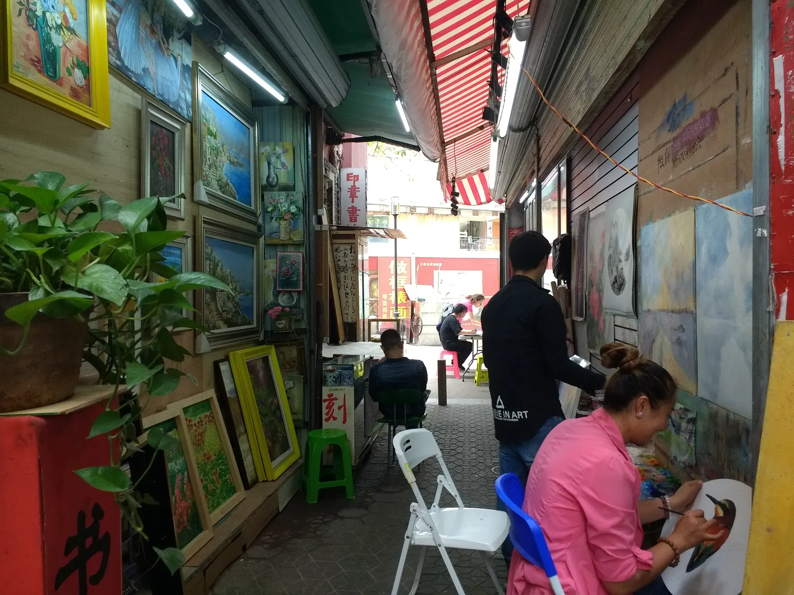 Painters at work on canvases in a Dafen oil painting village studio